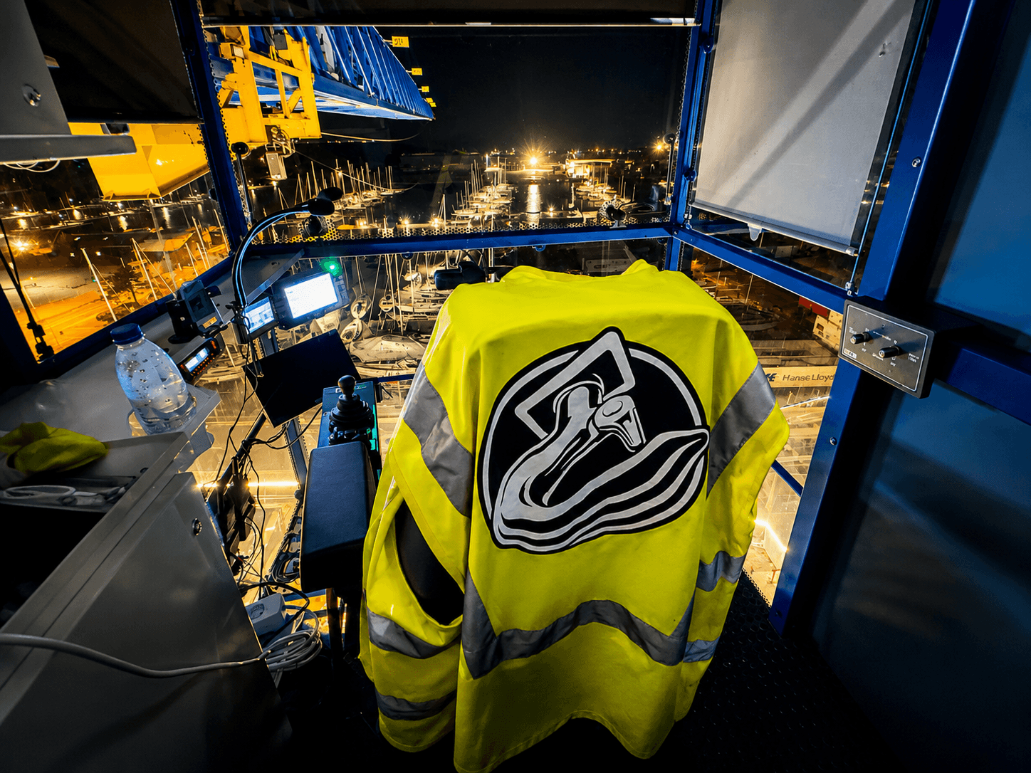 Tower crane operator cabin at the Nordhavn tunnel construction site with the KSR Cranes logo on a safety vest and a night view over the worksite.